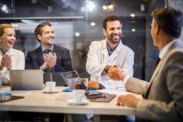 An insurance agent shaking hands with his insureds after celebrating having selecting the correct coverage.