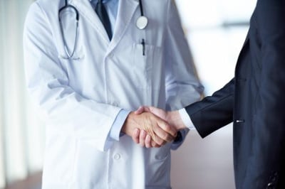 doctor handshake with a patient at doctors bright modern office in hospital